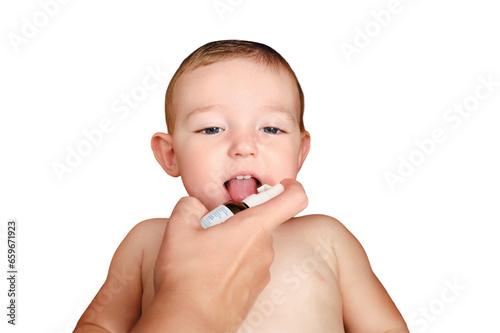 A mother woman sprays medicine into the mouth of a toddler baby boy, isolated on a white background. Mom gives a happy child liquid vitamins, isolated on a white background. Kid age one year