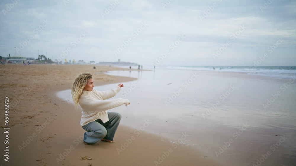 Woman throwing stones water ocean on cloudy day. Thinking girl resting seaside Woman throwing stones water ocean on cloudy day. Thinking girl resting seaside