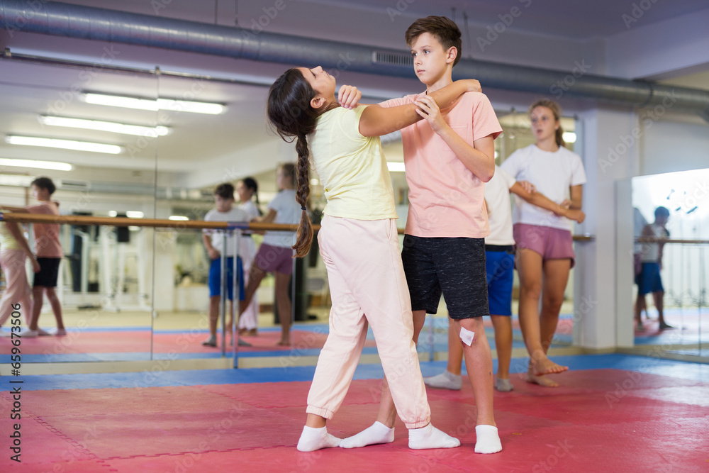 Group of young girls and boys training self-defence moves during group training.