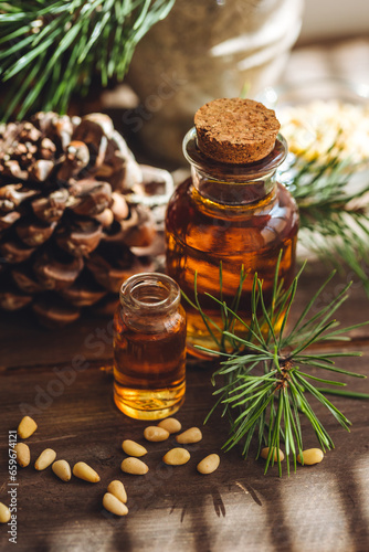 Organic essential oil, pine nuts, cedar cone on rustic wooden dark background. Concept of natural ingredients, naturopathy, herbal extracts and essence. Alternative medicine, aromatherapy