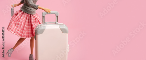 The doll carries a suitcase on wheels. Travel, vacation creative minimalistic concept. Banner with copy space.