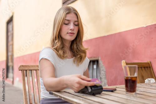 Young woman paying by credit card on terrace