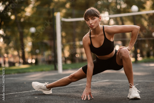 A young, athletic woman is exercising on the sports field. The concept of weight loss. Beautiful figure. Fintes exercise