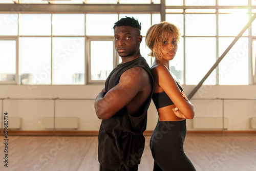young sporty african american couple in sportswear stands with their arms crossed in the gym