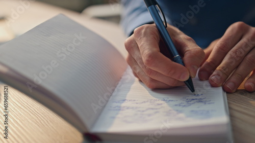 Closeup author hands writing notebook in office. Creative man noticing on paper