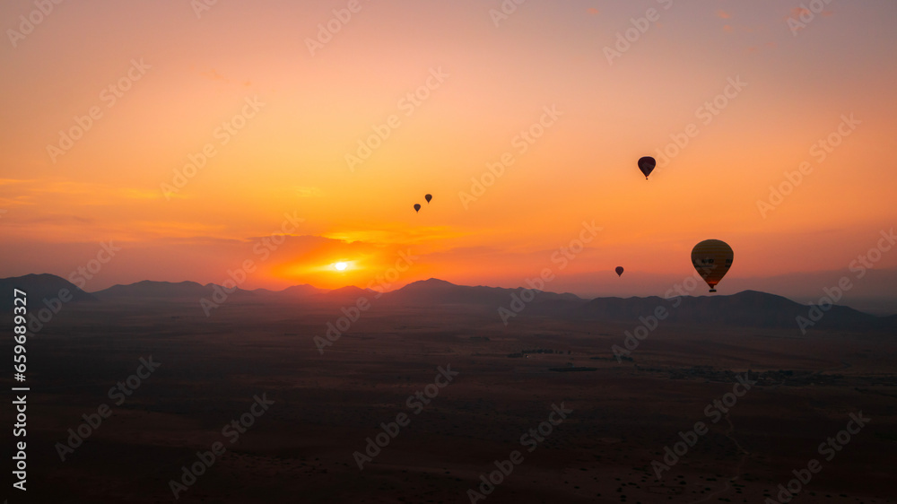 Hot balloon flying at sunset over the Atlas Mountains in the desert of Morocco 