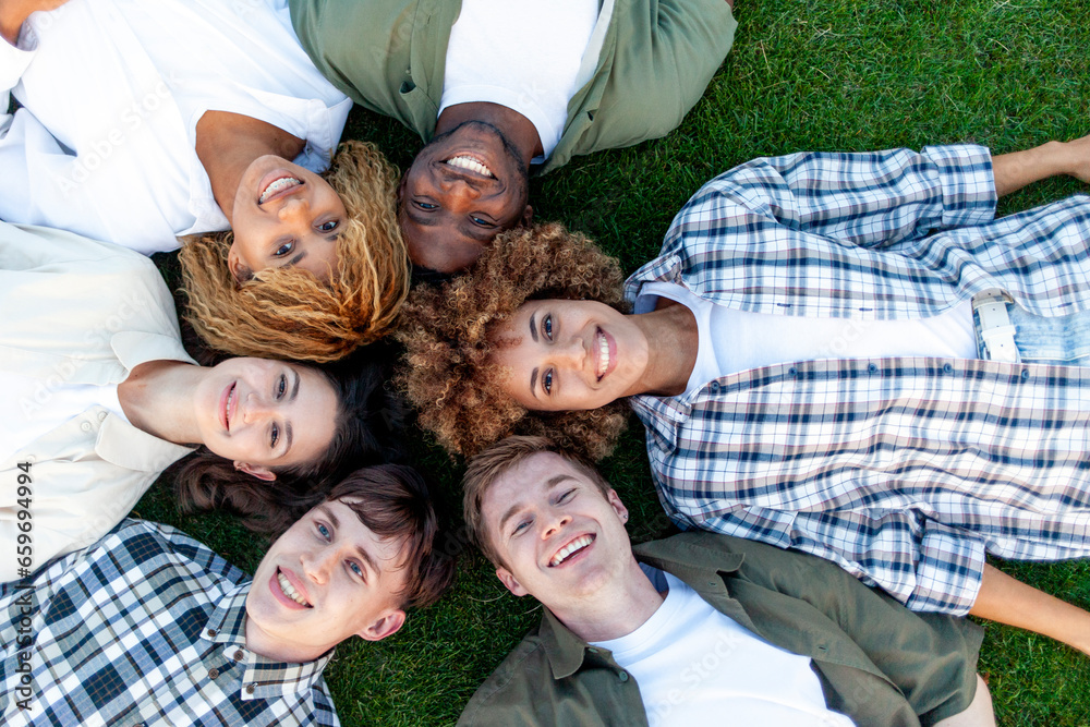 group of multiracial young people relax and lie together on grass in the park and smile, team of interracial students group of multiracial young people relax and lie together on grass in the park and smile, team of interracial students