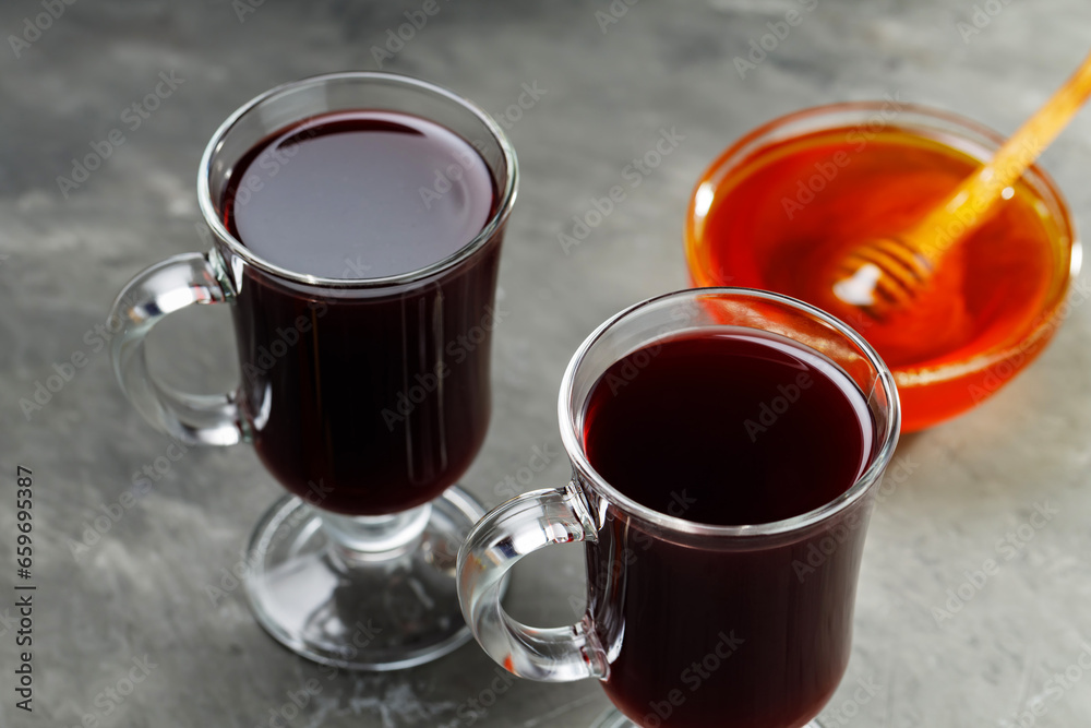 Two glasses of hot mulled wine with honey and spices on dark concrete background. Seasonal mulled drink Two glasses of hot mulled wine with honey and spices on dark concrete background. Seasonal mulled drink