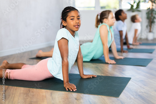 Children practicing yoga positions during group training in fitness center  performing stretching asana Urdhva Mukha Shvanasana