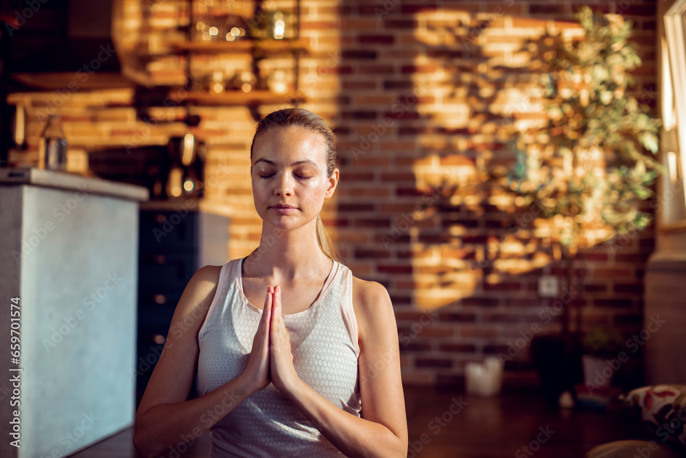 Young woman mediating in the living room of her home