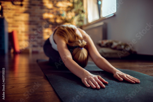 Fototapeta Naklejka Na Ścianę i Meble -  Young woman doing yoga on the floor of her living room at home