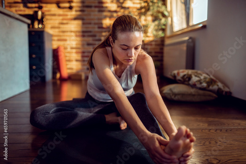 Young woman doing yoga on the floor of her living room at home