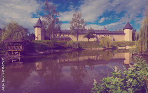 View of Sucevita monastery across pond in sunny autumn day, Romania