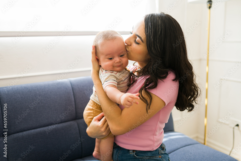 Beautiful mother giving a kiss to her cute baby Beautiful mother giving a kiss to her cute baby