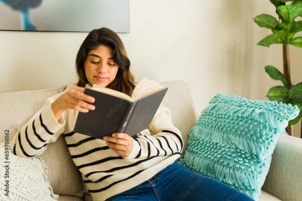 Smart latin woman enjoying her hobby reading a book on the sofa Smart latin woman enjoying her hobby reading a book on the sofa