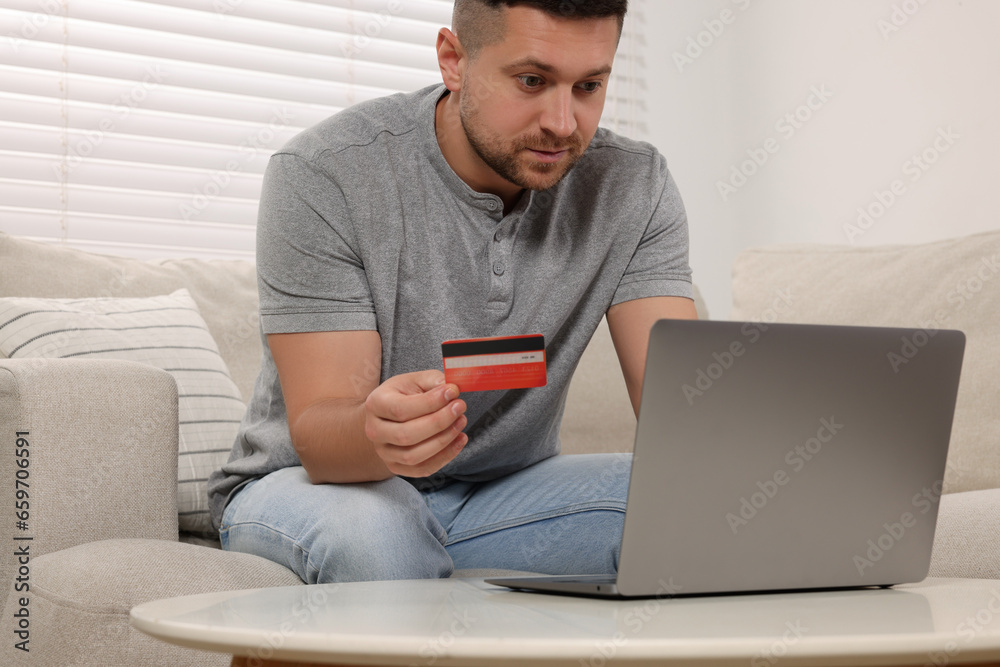 Handsome man with credit card using laptop for online shopping at home Handsome man with credit card using laptop for online shopping at home