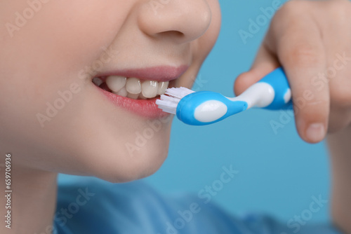 Girl brushing her teeth with toothbrush on light blue background  closeup