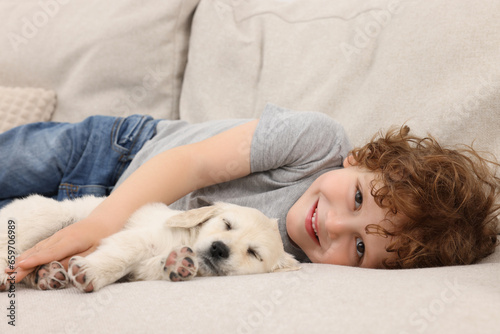 Little boy hugging cute puppy on couch