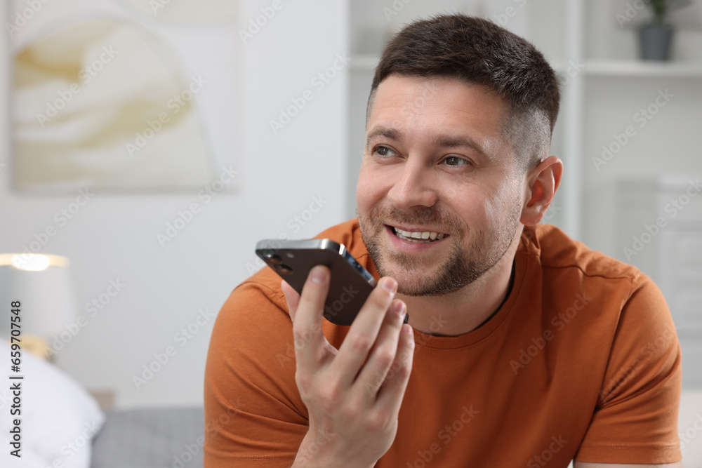 Handsome man recording voice message via smartphone at home Handsome man recording voice message via smartphone at home