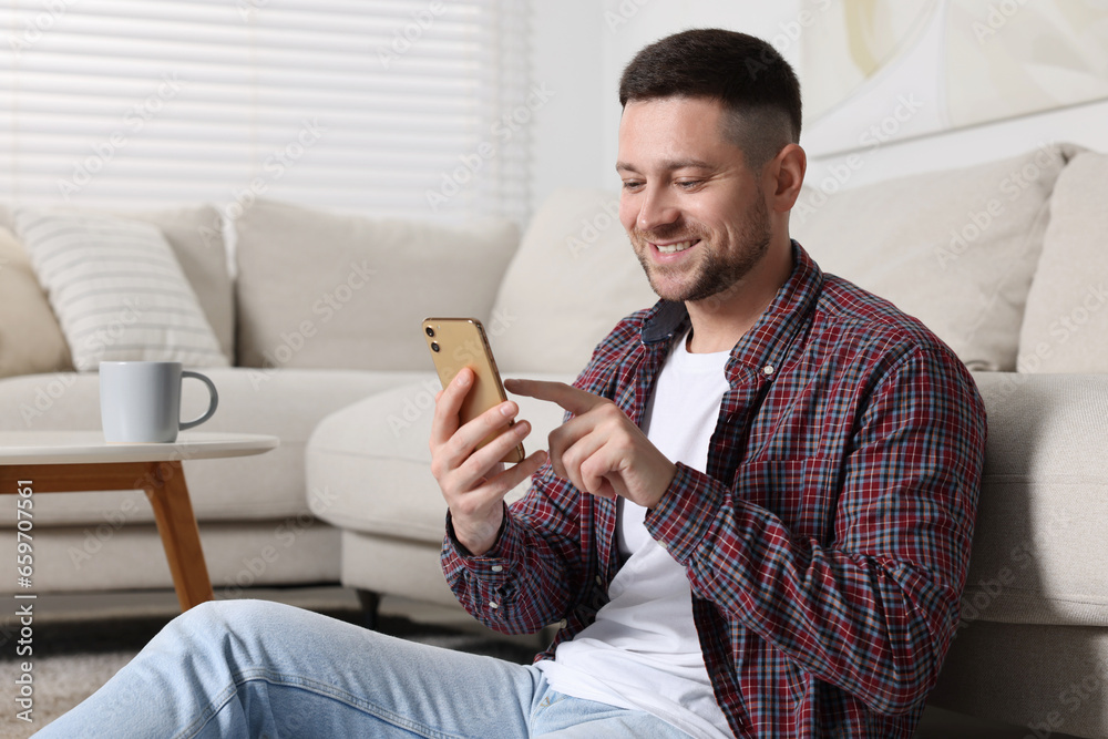 Handsome man typing message on smartphone at home Handsome man typing message on smartphone at home