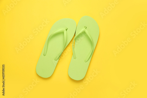 Stylish light green flip flops on yellow background, top view