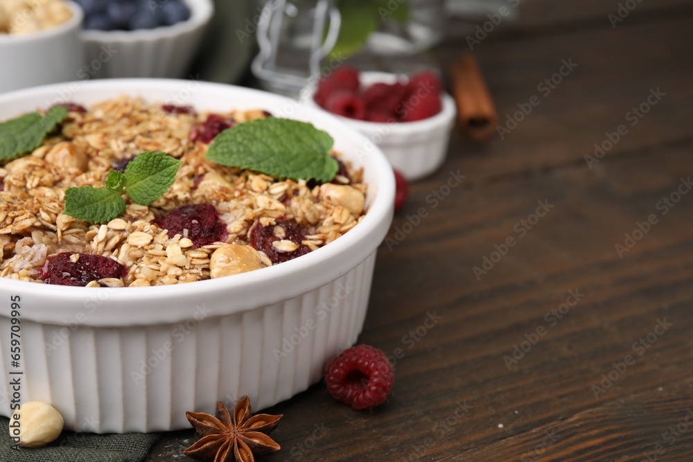 Tasty baked oatmeal with berries and nuts in bowl on wooden table, closeup. Space for text Tasty baked oatmeal with berries and nuts in bowl on wooden table, closeup. Space for text