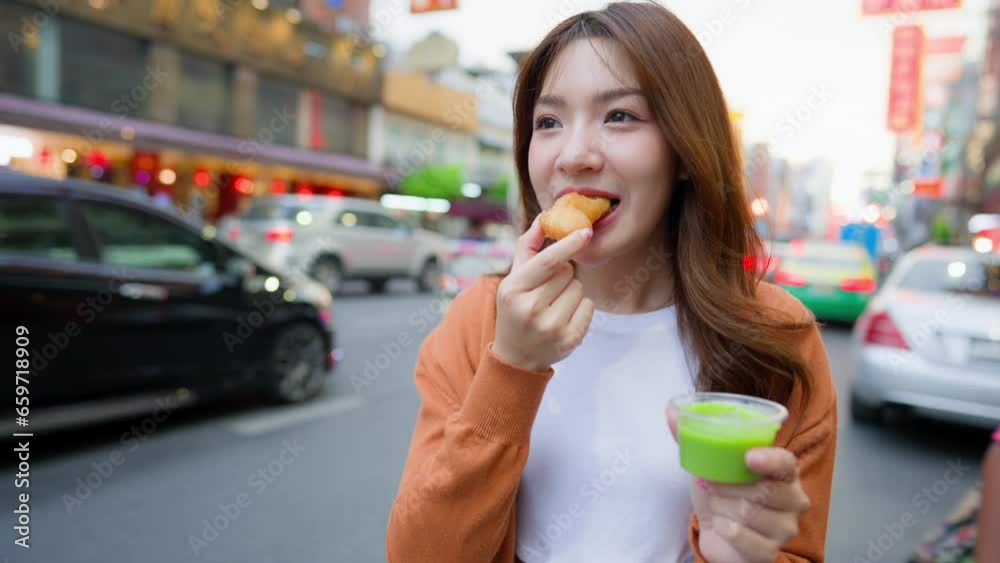 Young Asian tourists standing and eating Thai desserts. Young beautiful tourists in Chinatown street food market, Bangkok, Thailand Young Asian tourists standing and eating Thai desserts. Young beautiful tourists in Chinatown street food market, Bangkok, Thailand