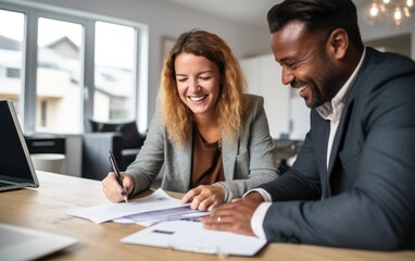 Mixed skin clients smiling signing a mortgage deal