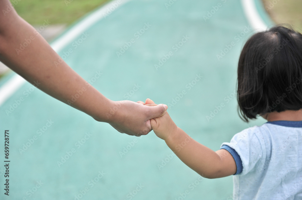 Mother leads her kid in summer forest nature outdoor. Trust, family, protection and help concept. Female and child's hands closeup against the background of summer greenery. Mother leads her kid in summer forest nature outdoor. Trust, family, protection and help concept. Female and child's hands closeup against the background of summer greenery.