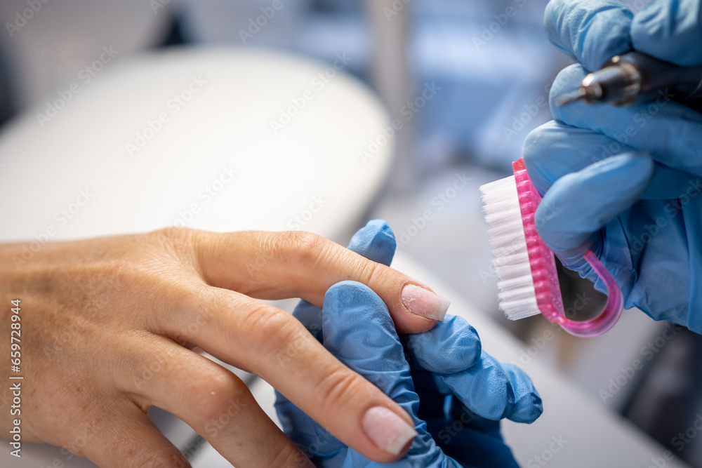 Nail care procedure in a beauty salon. Female hands and tools for manicure, process of performing manicure in beauty salon. Concept spa body care. Gloved hands of a skilled manicurist cutting cuticles