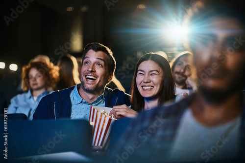 Young mixed couple watching a comedy in the movie theater