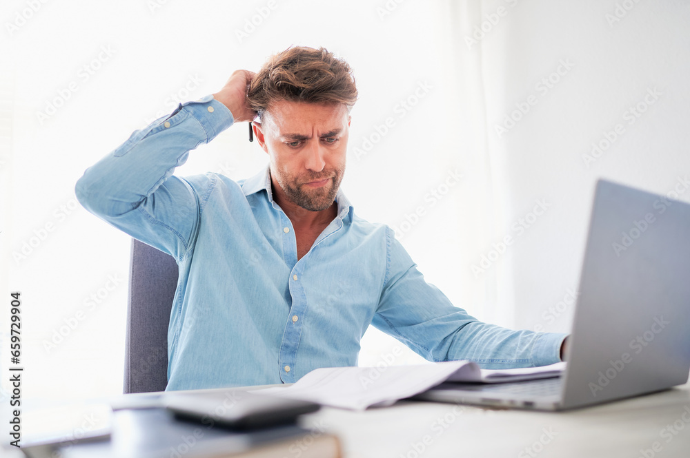 Mental health at work concept. Man scratches his head showing frustration gesture while working at his office desk. Mental health at work concept. Man scratches his head showing frustration gesture while working at his office desk.
