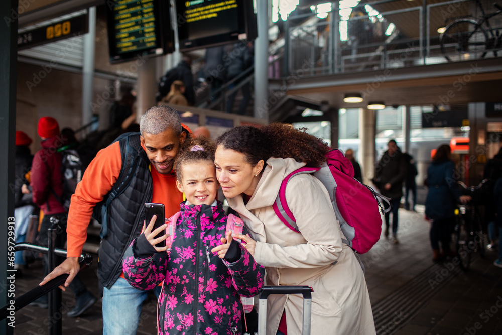 Young mixed family using a smartphone for train routes at the train station Young mixed family using a smartphone for train routes at the train station