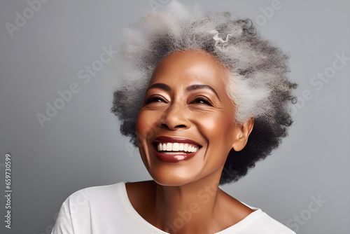 Smiling black adult woman touch face with smooth healthy skin. Open healthy smiling beautiful aging mature woman with white teeth. Beauty, dental and cosmetics skincare advertising concept