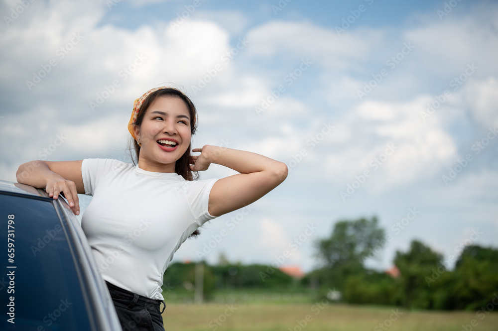 A happy woman feeling fresh, enjoying the wind outside the car and having fun during her road trip. A happy woman feeling fresh, enjoying the wind outside the car and having fun during her road trip.