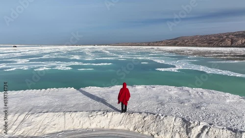 A woman in red dress standing at the Mangya emerald lake in QInghai province, China.