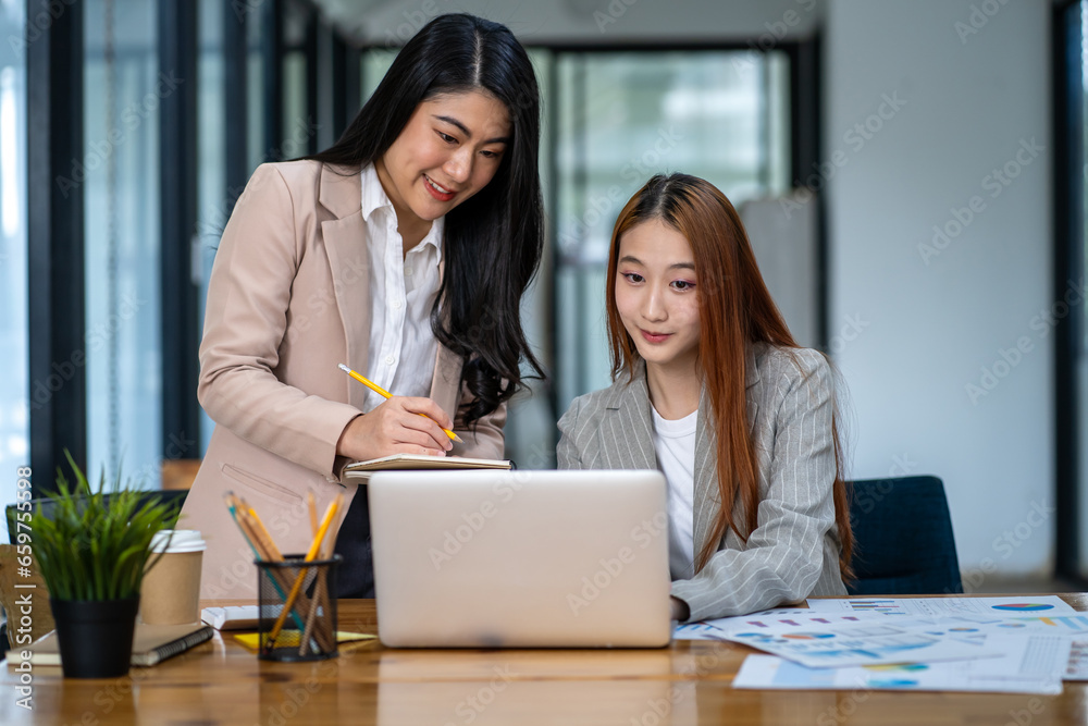Two Asian businesswomen working together on digital tablet Female executive meeting and having a creative discussion in office using tablet PC and smiling Two Asian businesswomen working together on digital tablet Female executive meeting and having a creative discussion in office using tablet PC and smiling