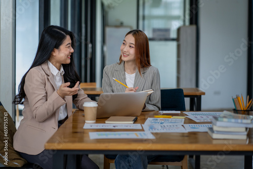 Two Asian businesswomen working together on digital tablet Female executive meeting and having a creative discussion in office using tablet PC and smiling