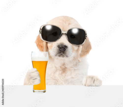 Golden retriever puppy with light beer peeking above white banner. isolated on white background. © Ermolaev Alexandr