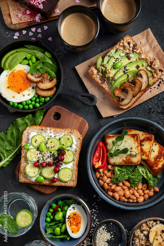 Tasty food with avocado toast, vegetables, eggs on dark background. Helthy breakfast concept