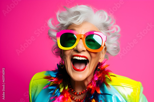 Happy senior retired woman in colourful neon clothes  isolated on pink background