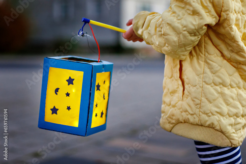 Closeup of little preschool kid girl holding selfmade traditional lanterns with candle for St. Martin procession. child happy about family parade in kindergarten. German tradition Martinsumzug photo