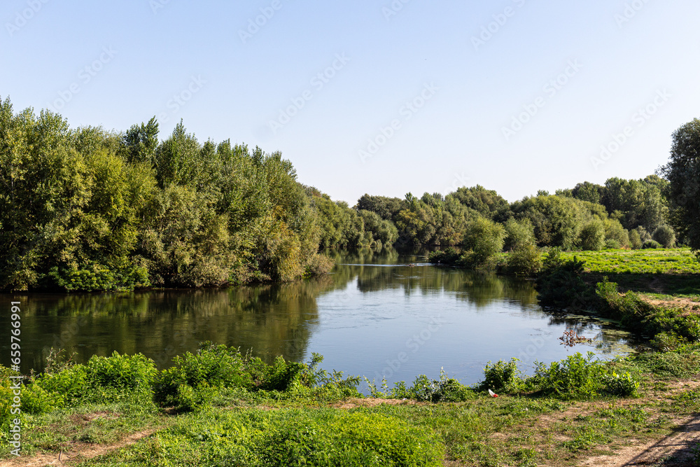 Landscape with river, trees and blue sky