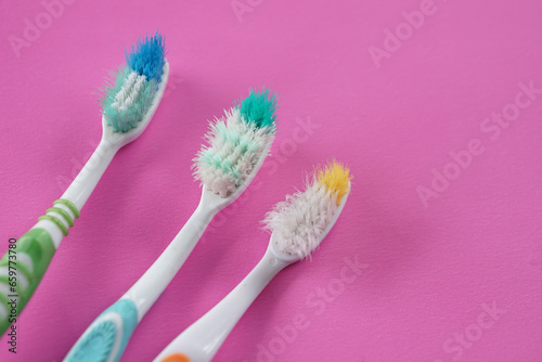 Three used, old toothbrushes on pink background. Concept, tool for brush teeth. Need to change new one from long time using toothbrush for efficiency of dental cleaning.                               