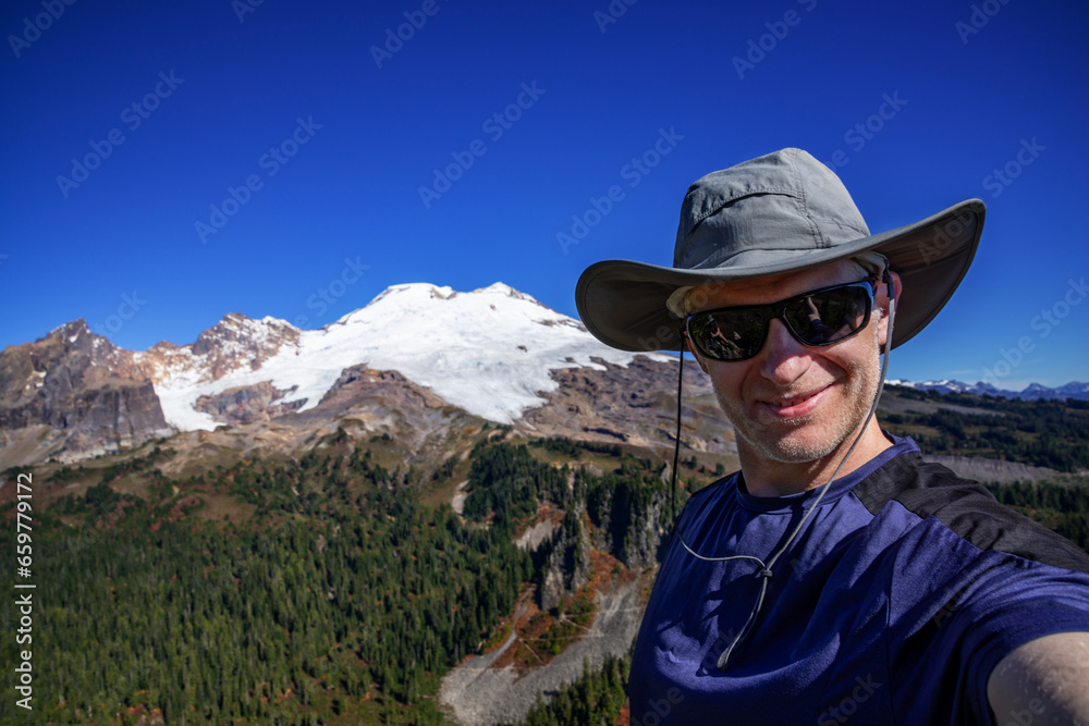 Adventurous athletic male hiker taking a selfie with the sun shinning and Mount Baker in the background.
Adventurous athletic male hiker taking a selfie with the sun shinning and Mount Baker in the background.