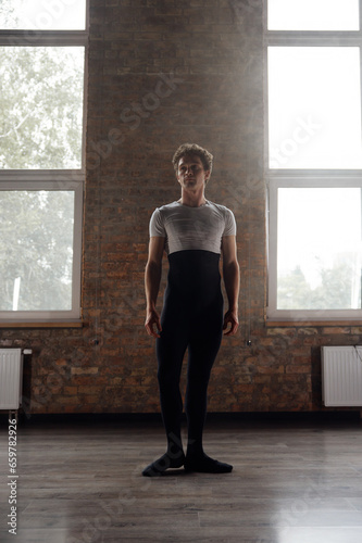 Full-length portrait of handsome athletic ballet dancer in studio room