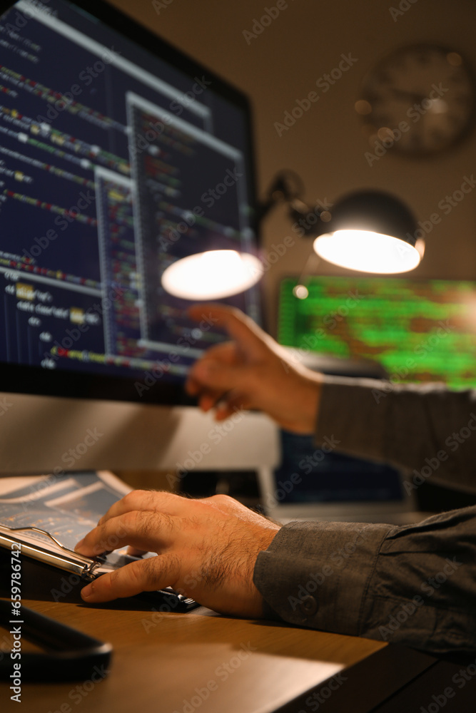 Male programmer working in office at night, closeup