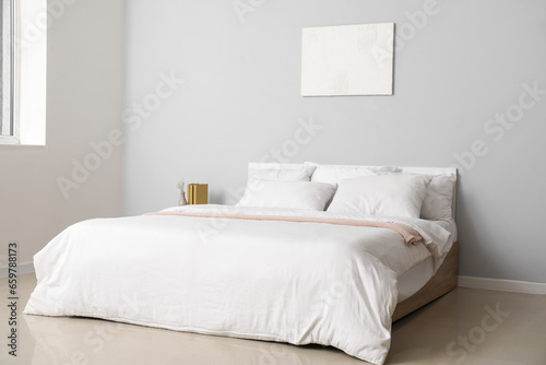 Interior of light bedroom with large double bed and white pillows