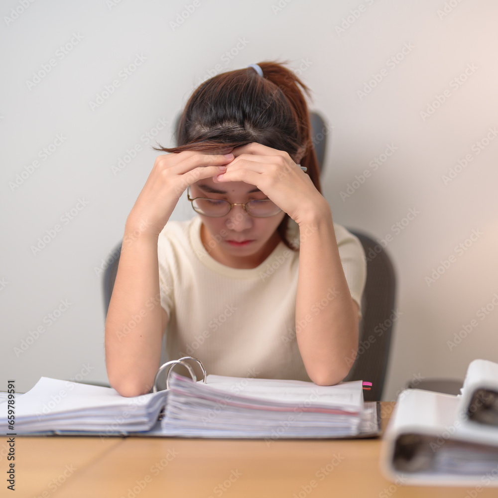 Asian woman having Tired and Stressed while working, female businesswoman having headache and Migraine at office, Exhausted woman with document folder stack at home late night. Overworked and Overtime Asian woman having Tired and Stressed while working, female businesswoman having headache and Migraine at office, Exhausted woman with document folder stack at home late night. Overworked and Overtime