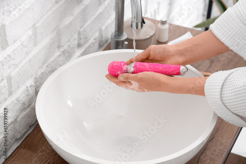 Woman washing vibrator over sink, closeup